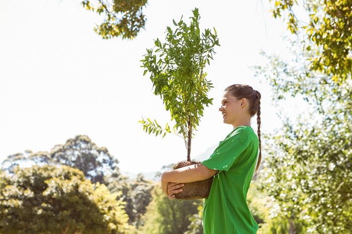 woman holding a young tree to promote sustainable future
